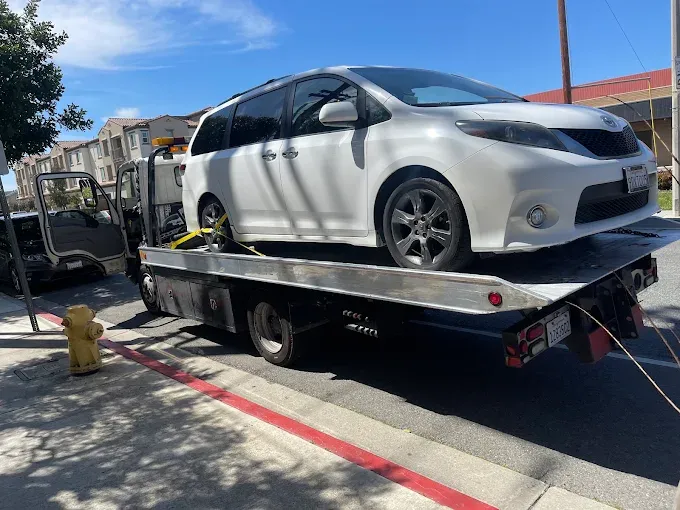 Minivan loaded and strapped onto a Mondragon Towing flatbed